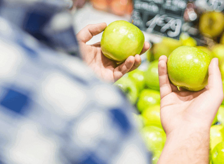 Consumer comparing apples on a retail display